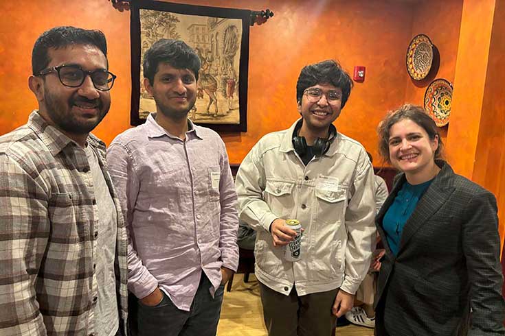 Four students and alums stand in a line smiling at the camera.