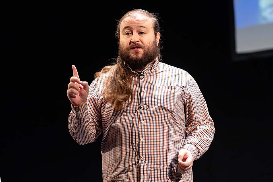 Jonathan Schaffer presents in front of a slide with hand raised.
