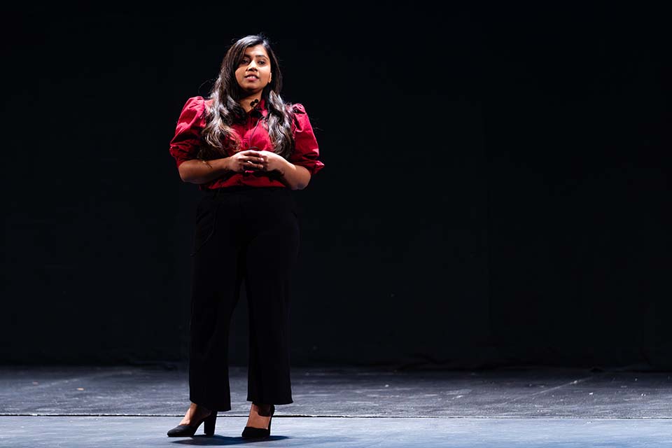 Samitha Ranasinghe stands presenting onstage.