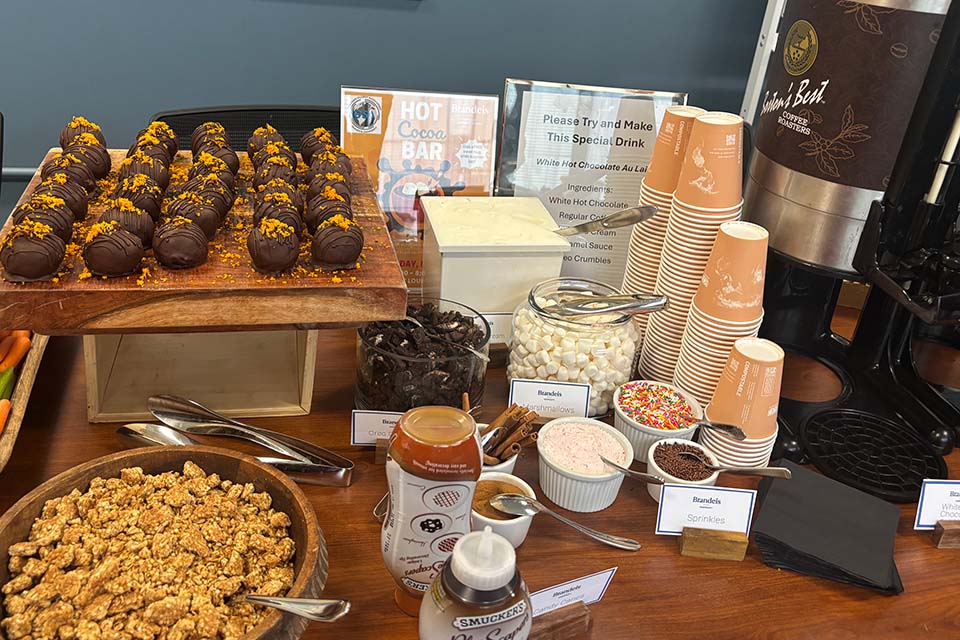 Cups, a hot drink dispenser, and various cocoa toppings on a table.