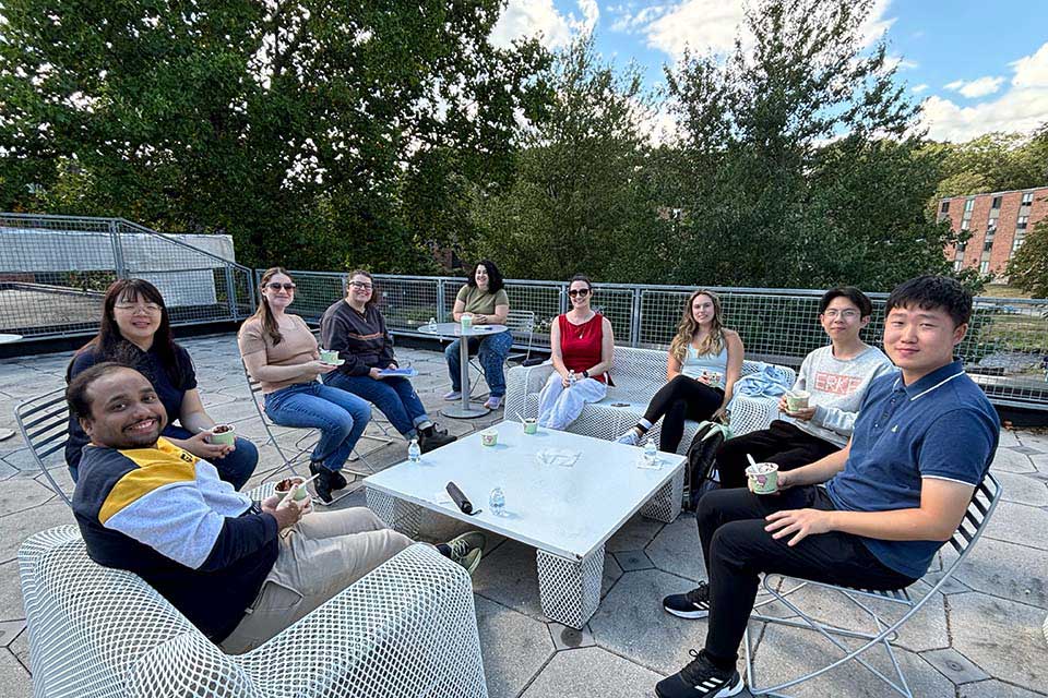 A group of students sit around an outside table with ice cream.