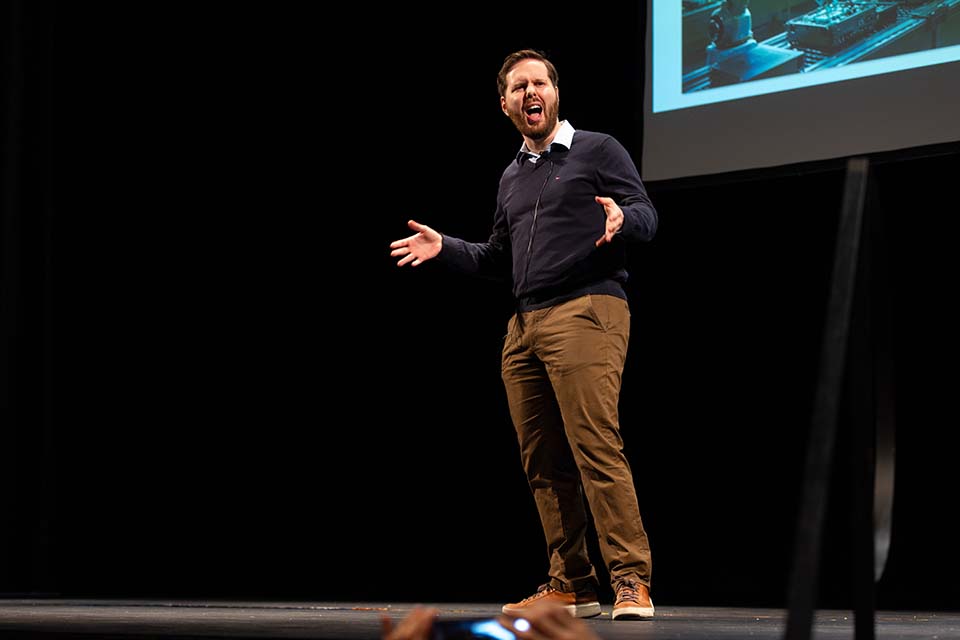 Josh Perlmutter presents onstage in front of a slide.