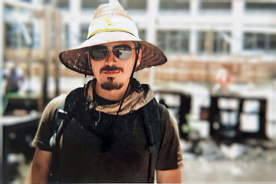 Ryan Collins, wearing a straw hat and sunglasses, in the field in Miami