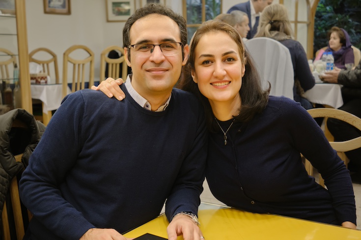 Kamran Geshnizjani and Maryam Ziari sit side by side at a table, with her arm around him.