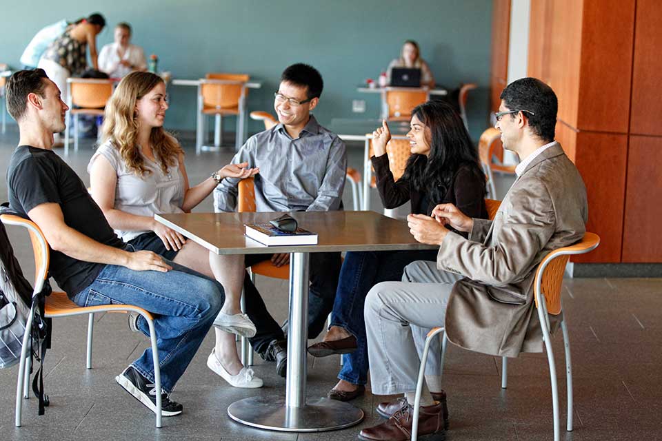 Graduate students sit at a table talking