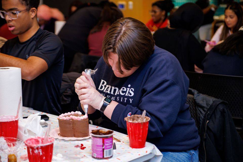 A student frosts a heart-shaped cake.