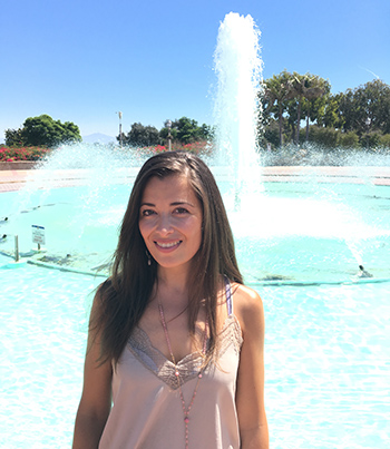kelly andriamasindray standing in front of pool with fountain