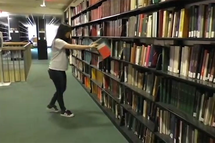 Student in the library putting books back on the shelf