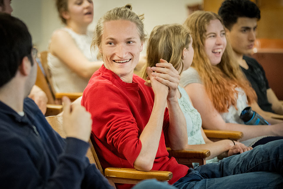Smiling students in a classroom talking