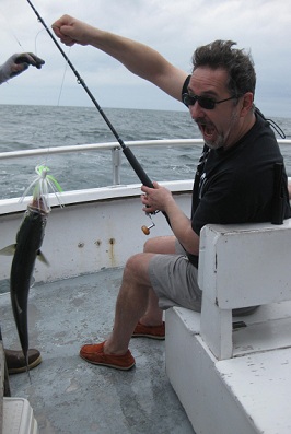 David Powelstock reeling in a fish on a boat