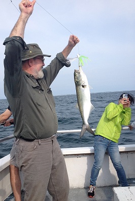Steve Dowden holding a fish on a line with Jian Wei covering her face