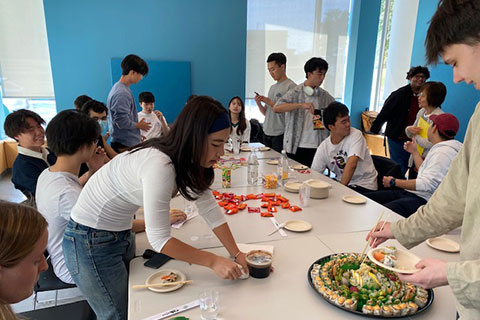 Students serve themselves lunch around a table.