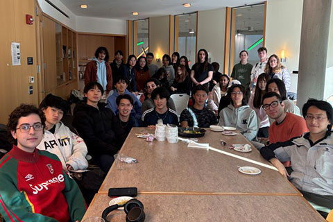 A group of students pose for a photo around a table.