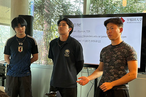 Three students stand in a classroom and give a presentation.