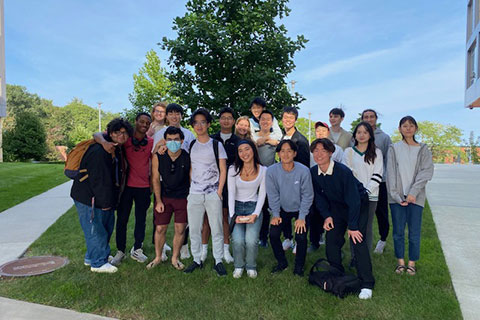 A group of students pose for a photo outside on the Brandeis campus.