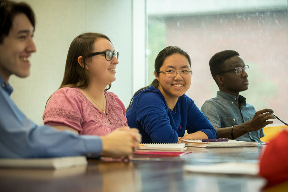 Four students seated at a table in a classroom