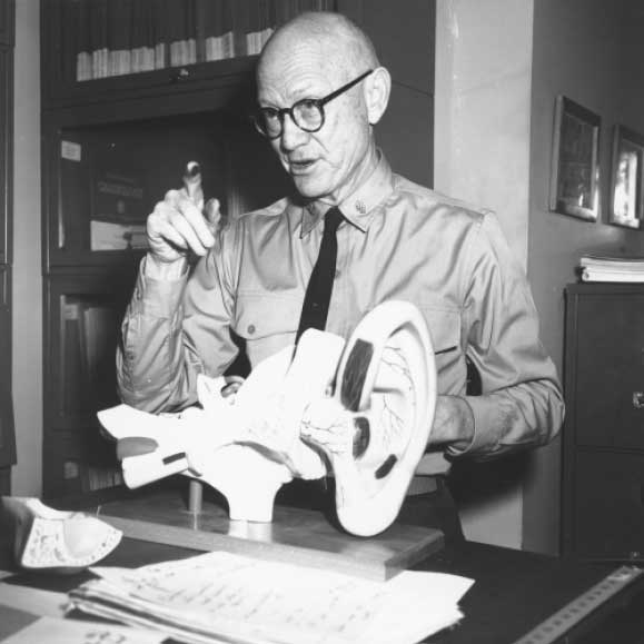 Ashton Graybiel explaining something, standing next to a large model of an ear