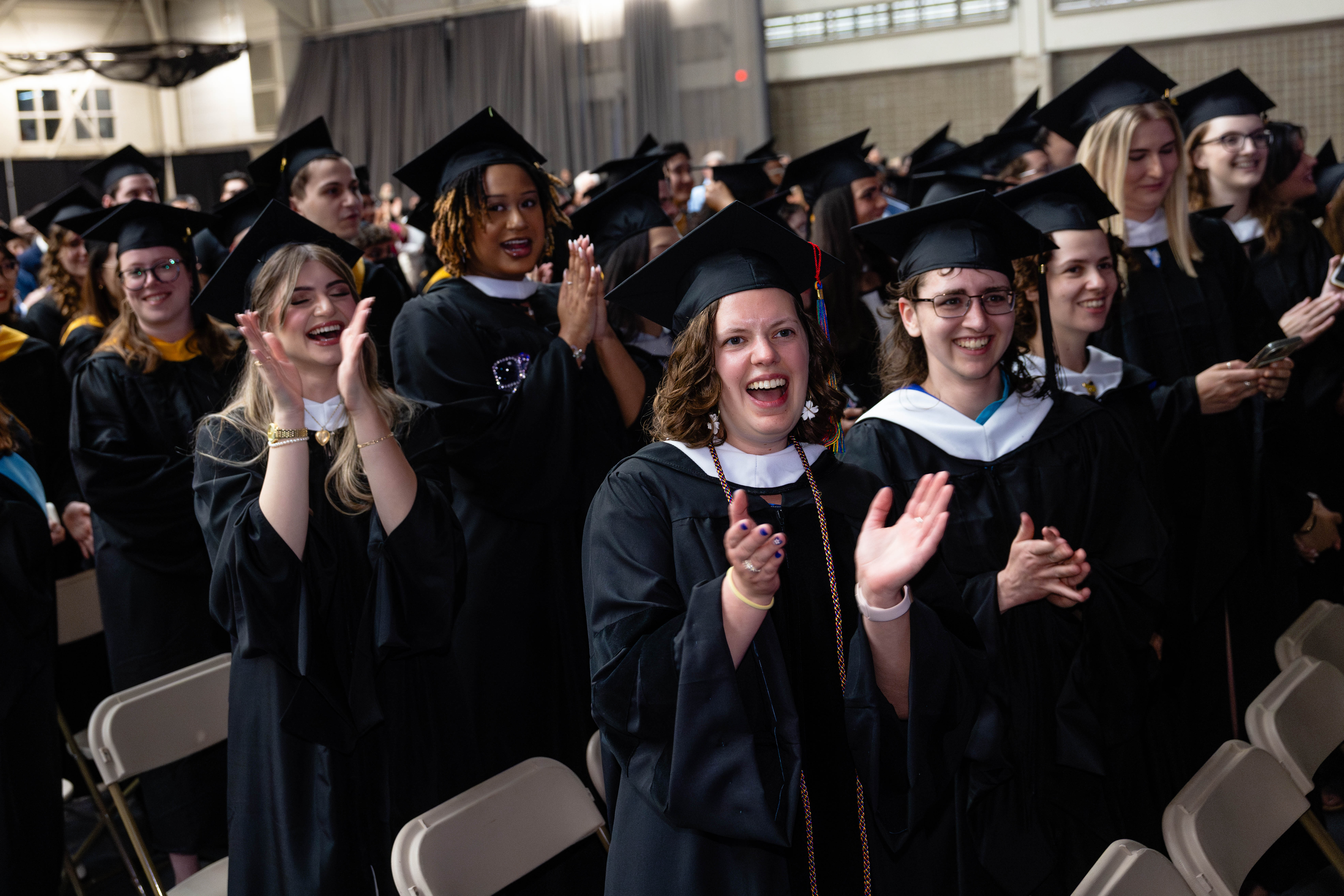 Students in regalia applaud.