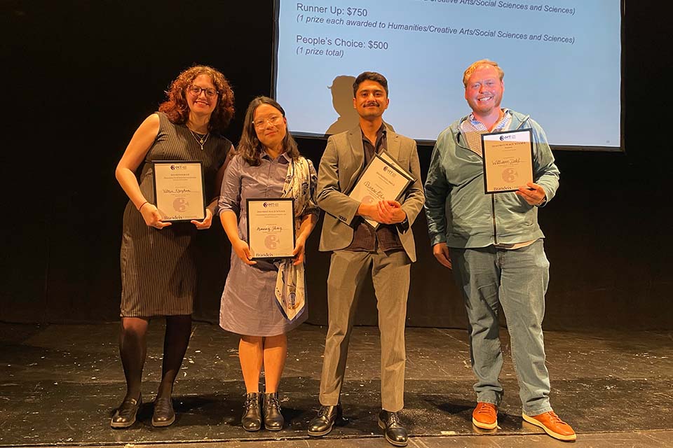 Victoria Khaghani, Manning Zhang, Pranav Ojha, and William Dahl stand onstage holding their Three Minute Thesis prize certificates.