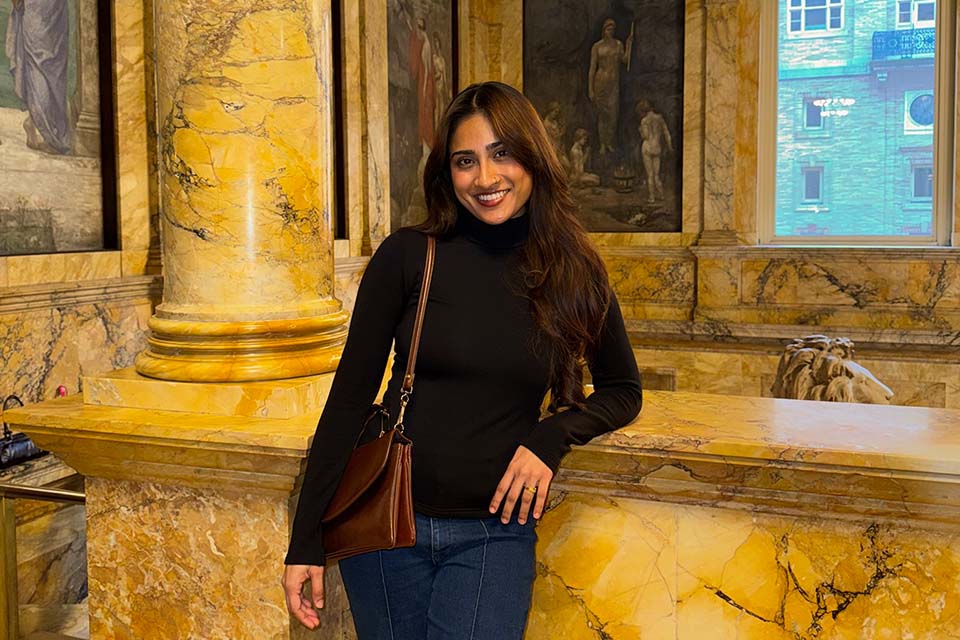Atiqua Prithu stands against a marble stairwell in an art museum.