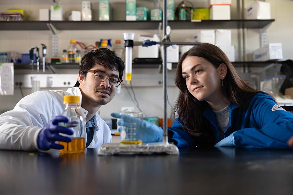 Two students work with lab equipment.