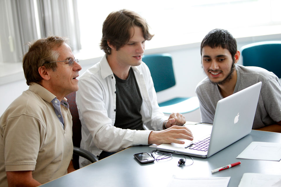Professor working with students on a computer