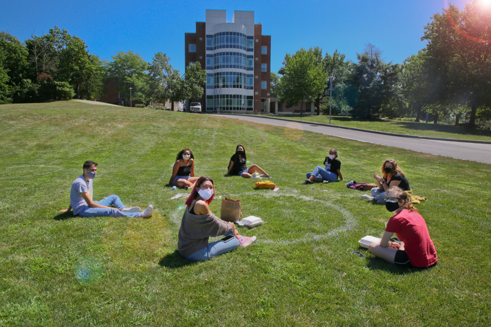 Students sitting on the grass on a sunny day.