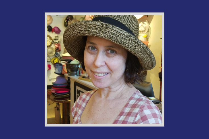 image of Allegra Goodman, a White woman with brown hair, wearing a woven hat with a wide brim, and a red and white-checked top