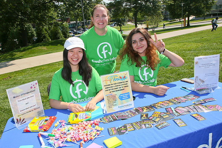 Students wearing green shirts sit at a table at Fresh Check Day