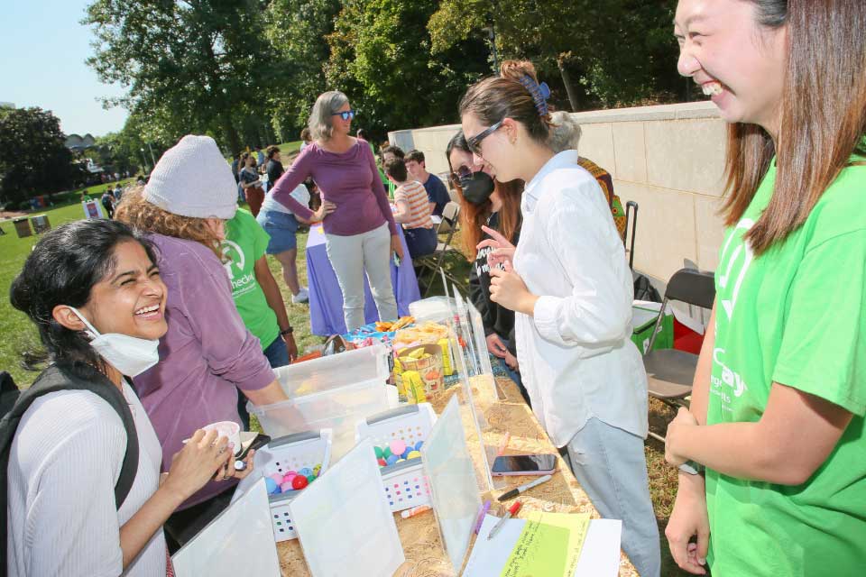 Two students smile at each other across the UBelong booth