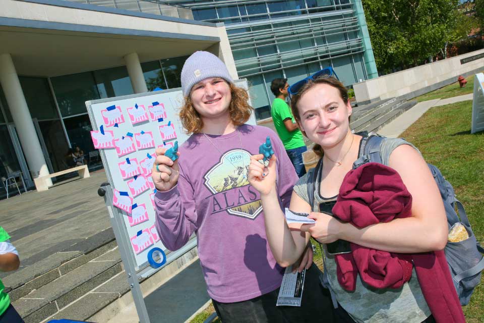 Two students holding elephants at the Elephant in the Room booth