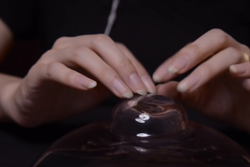 Screenshot from a video of ASMR tapping with the image showing two hands tapping on glass