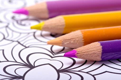 Close up image of colored pencils resting on a blank coloring page