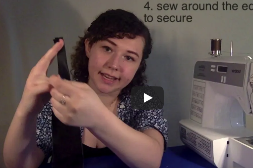 A picture of Rosie Sentman '21 holding up a piece of fabric in front of a sewing machine