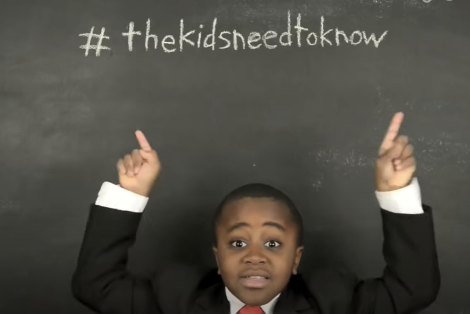 A kid dressed up as president pointing to the hashtag 'the kids need to know'.