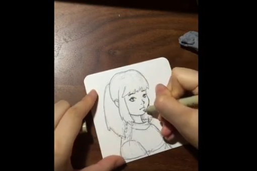 Closeup of hands drawing an anime girl