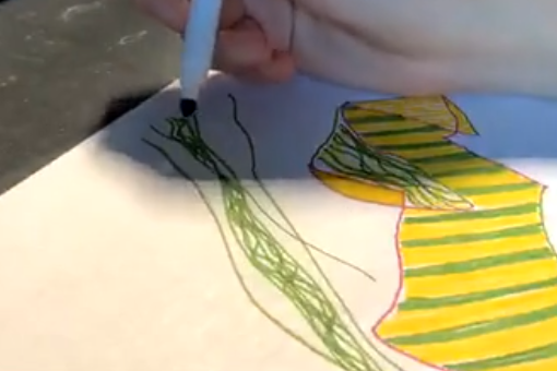 A close up image of a hand holding a marker and drawing green and yellow lines