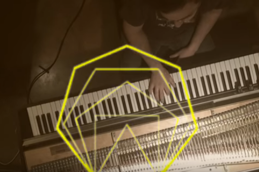 Image of a man playing the keyboard with an overlay of a yellow geometric hexagon
