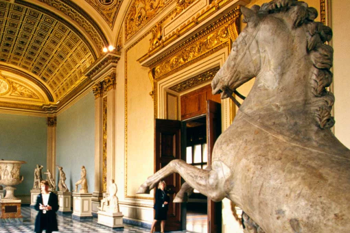 Image from the interior of a museum with a gallery of sculptures and a statue of a horse leaping in the foreground