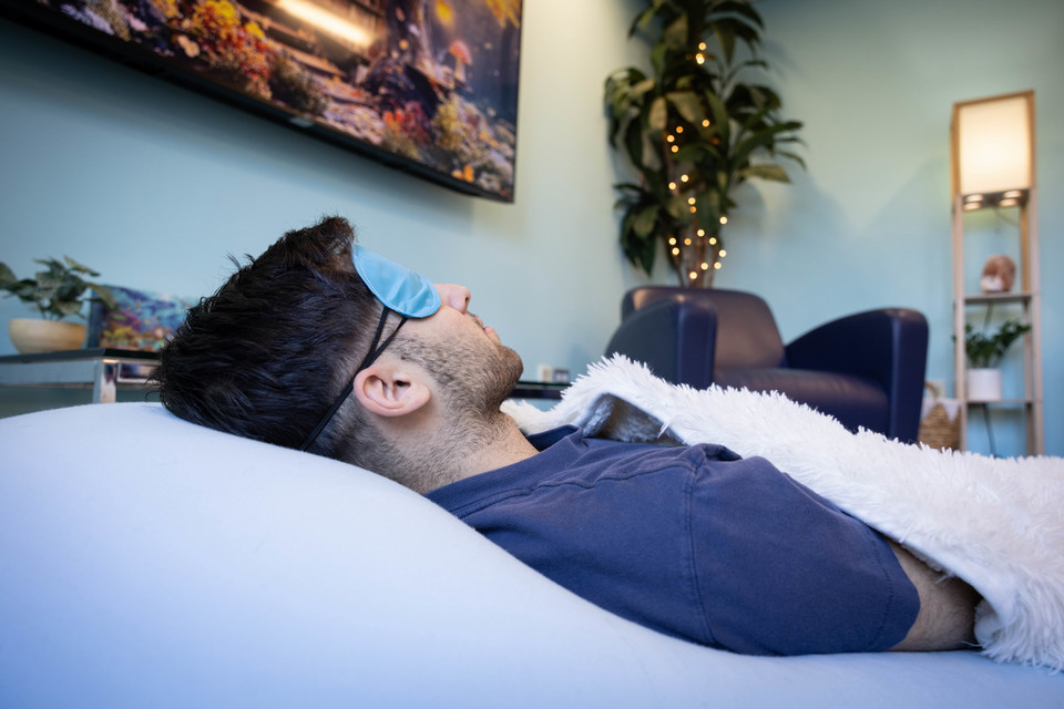 A student naps on a beanbag with a blanket and sleep mask