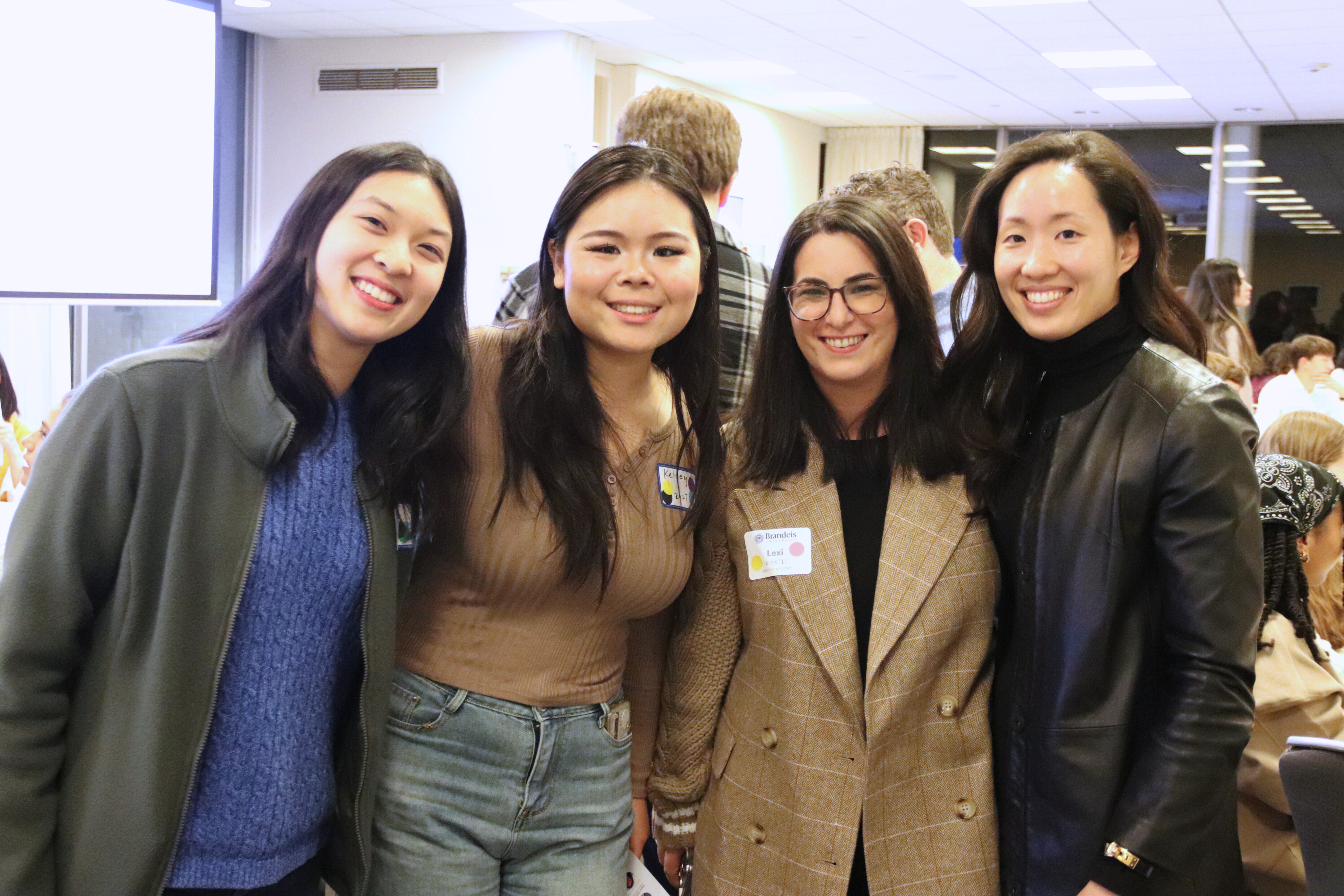 Two Brandeis alum pose for a photo with two students during Deis Dinner 2024.