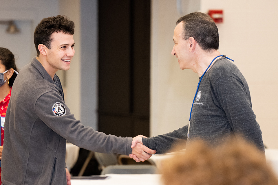 A student shakes hands with an alumnus.