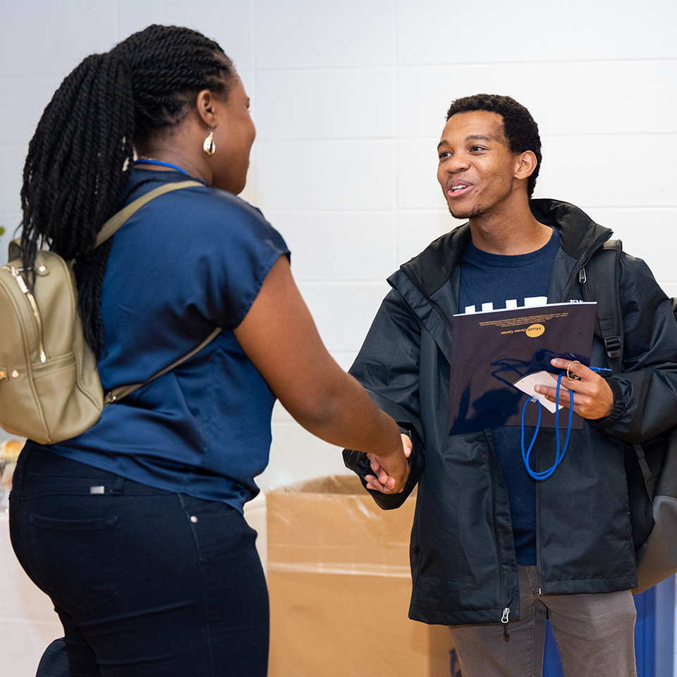 A student shakes hands with an alum during Deis Dinner 2022