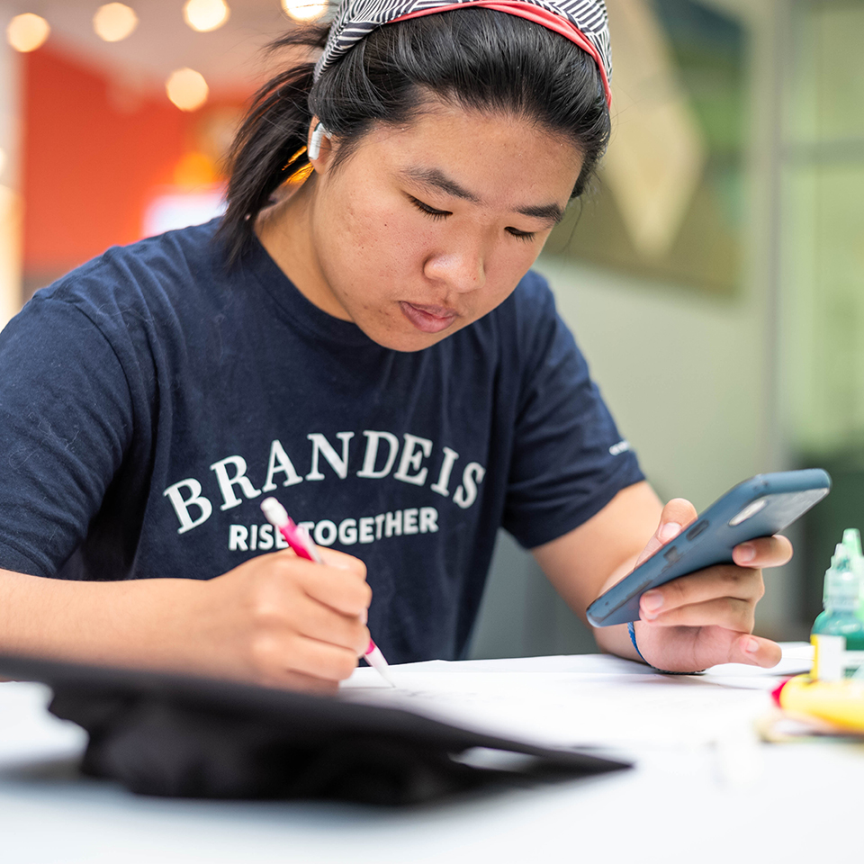 Emily Su ’23, sketches out a design she will use to adorn her mortarboard for her upcoming commencement ceremony during a graduation cap decoration event at the Shapiro Campus Center on May 16, 2023. Photo/Gaelen Morse