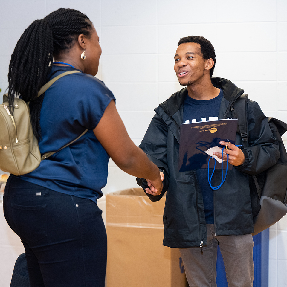 A student shakes hands with an alum during Deis Dinner 2022