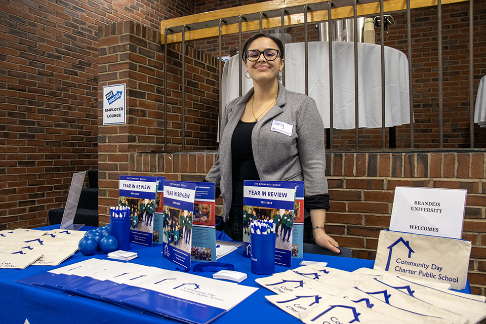 An employer poses with their table at a career fair.