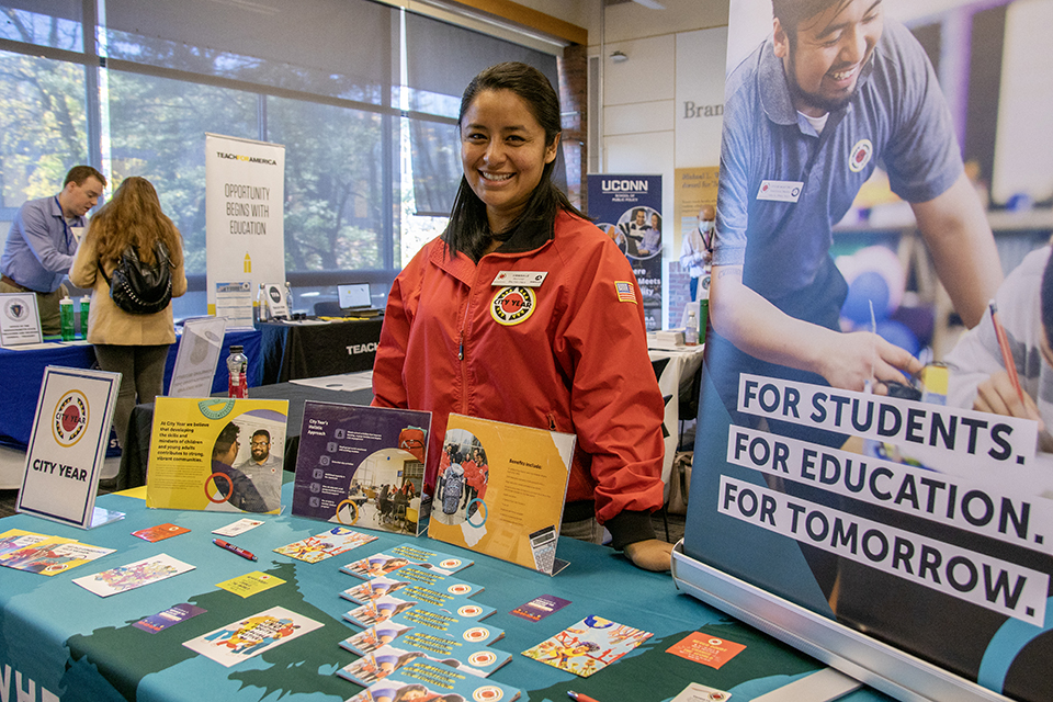 An employer poses with their table during a career fair