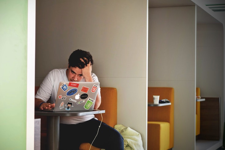 student sitting at desk looking at laptop feeling stressed out