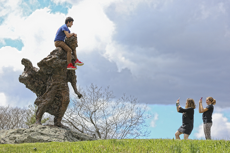 A student gets their picture taken atop the Louis D. Brandeis statue.