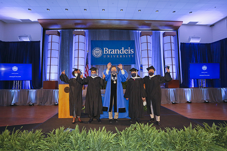 President of Brandeis, Ronald D. Liebowitz, poses with students during the 2021 Walk the Stage commencement event.